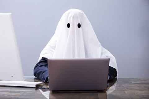 The ghostwriter. A ghost at its laptop. What does it cost to hire a ghostwriter? The ghost knows.