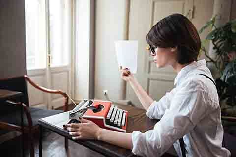 Woman author at typewriter. Will her work require editing or a rewrite?